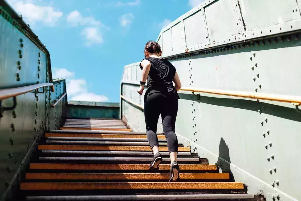 rear view of young woman running upstairs in art district, city downtown