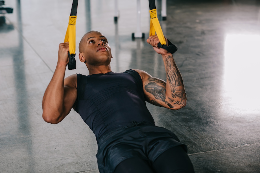 Ejercicios de abdominales con el entrenador de suspensión para un tronco fuerte como una roca