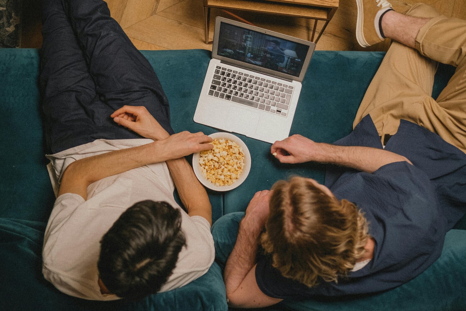 Hombres comiendo palomitas mientras una mujer está en una computadora portátil