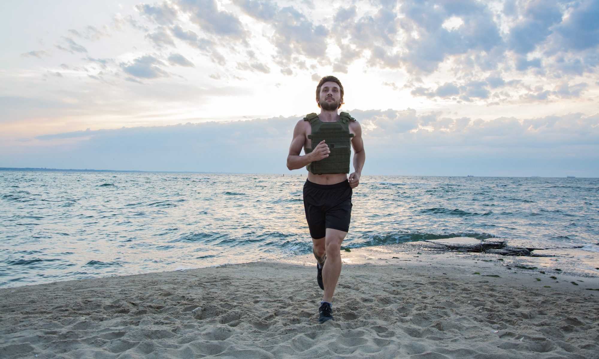 Hombre caminando trotando corriendo usando chaleco con peso al aire libre playa workout