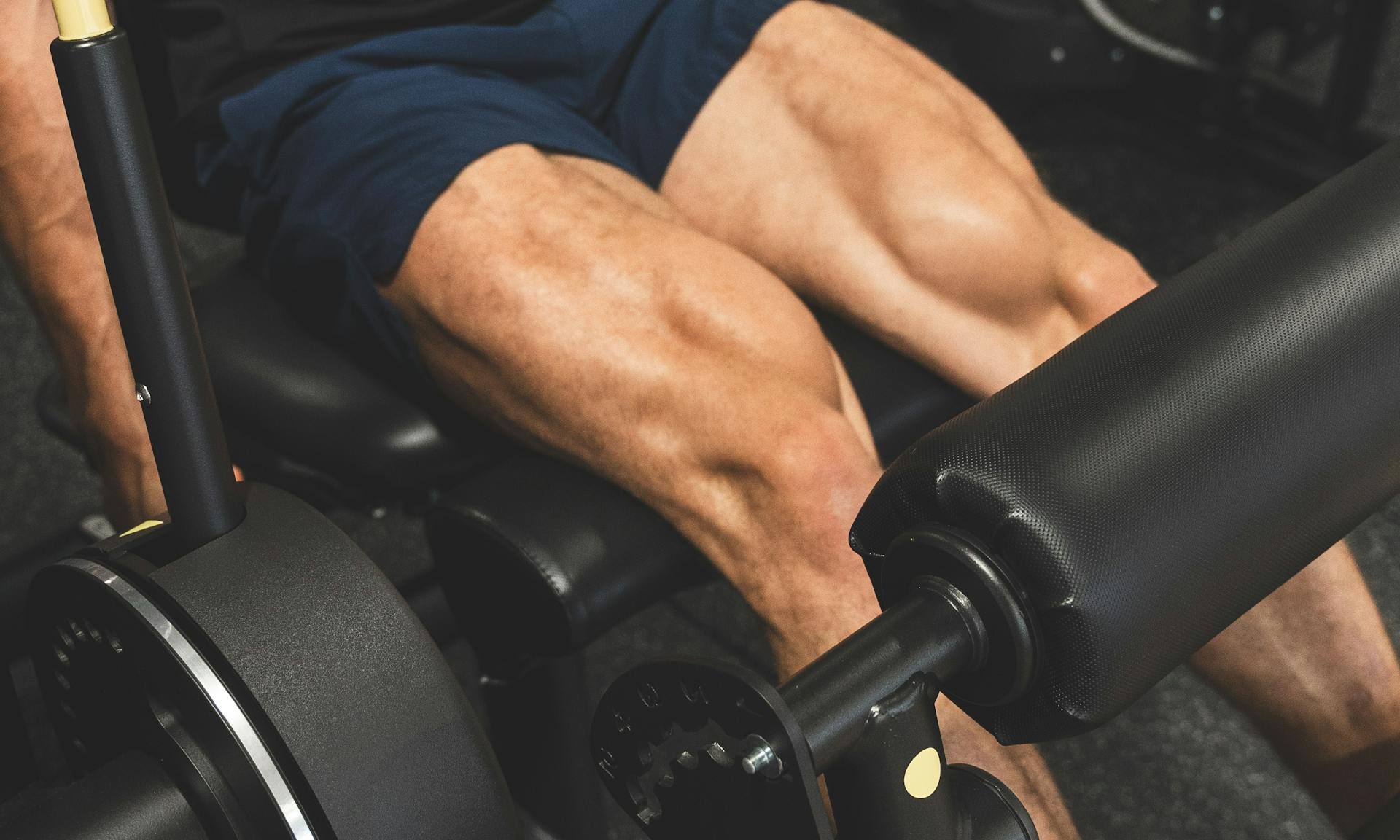 Hombre haciendo curl de pierna en máquina en el gimnasio
