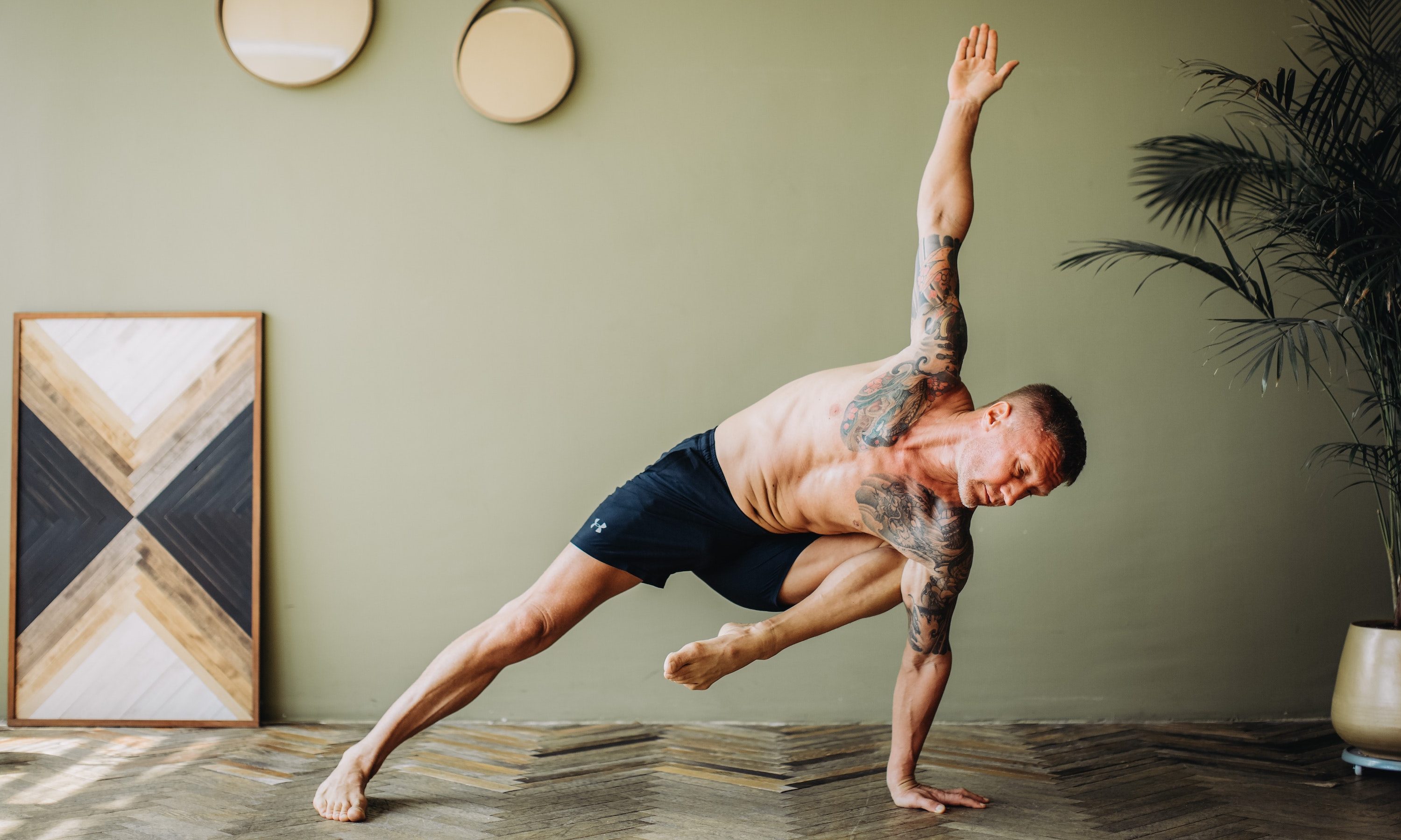 Hombre haciendo una pose de plancha lateral en yoga.